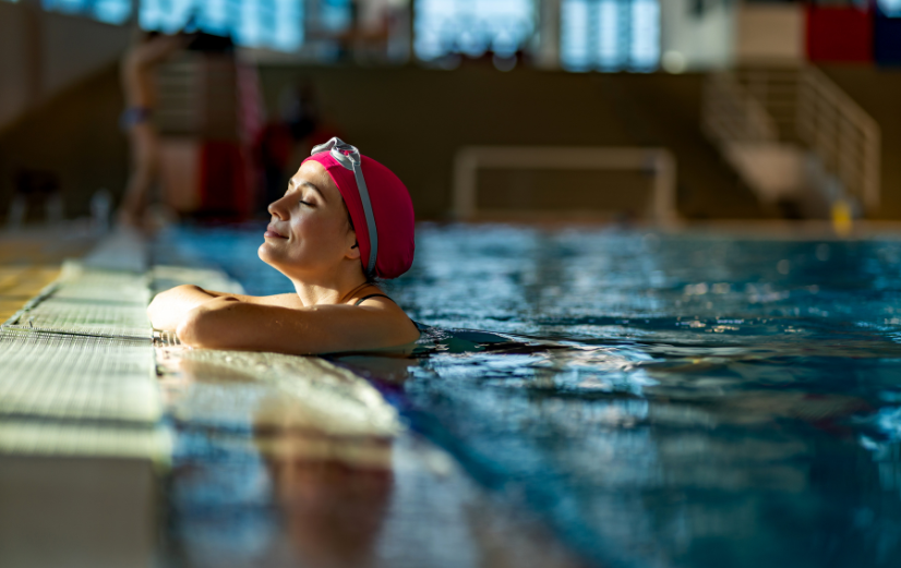 Frau lehnt sich entspannt am Rand des Pools zurück und wirkt zufrieden und ausgeglichen – dank einer guten Balance ihrer Neurotransmitter.